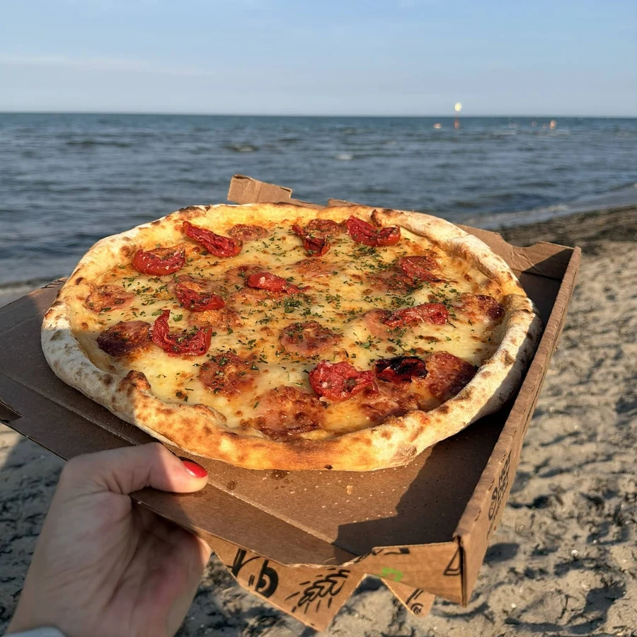 La pizza Abbronzatissima di Pizza Smile, con pomodorini confit e salamino, fotografata in spiaggia.